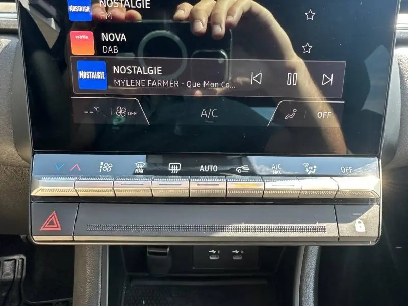 Gros plan sur la console centrale tactile du Renault Captur 2025, avec commandes climatisation et boutons argentés.