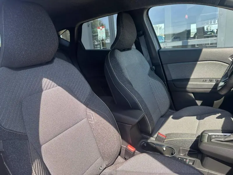 Vue intérieure côté avant droit du Renault Captur 2025, sièges tissu gris et accoudoir central noir.