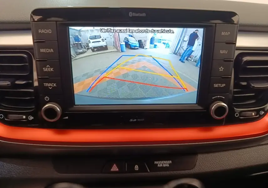 Écran tactile central de la Kia Stonic 2019 affichant la caméra de recul avec guidage coloré, tableau de bord noir et orange.