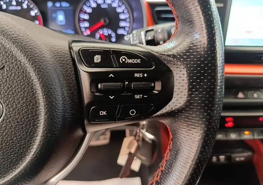 Gros plan sur le volant cuir perforé avec commandes multifonctions du Kia Stonic 2019, tableau de bord et écran tactile en arrière-plan.