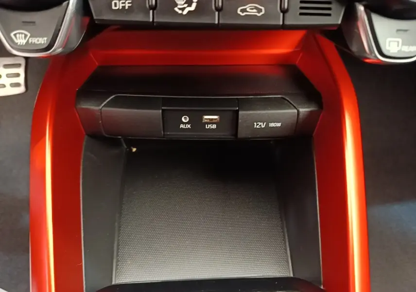 Gros plan sur la console centrale rouge du Kia Stonic 2019, avec prise AUX, USB et prise 12V visible.