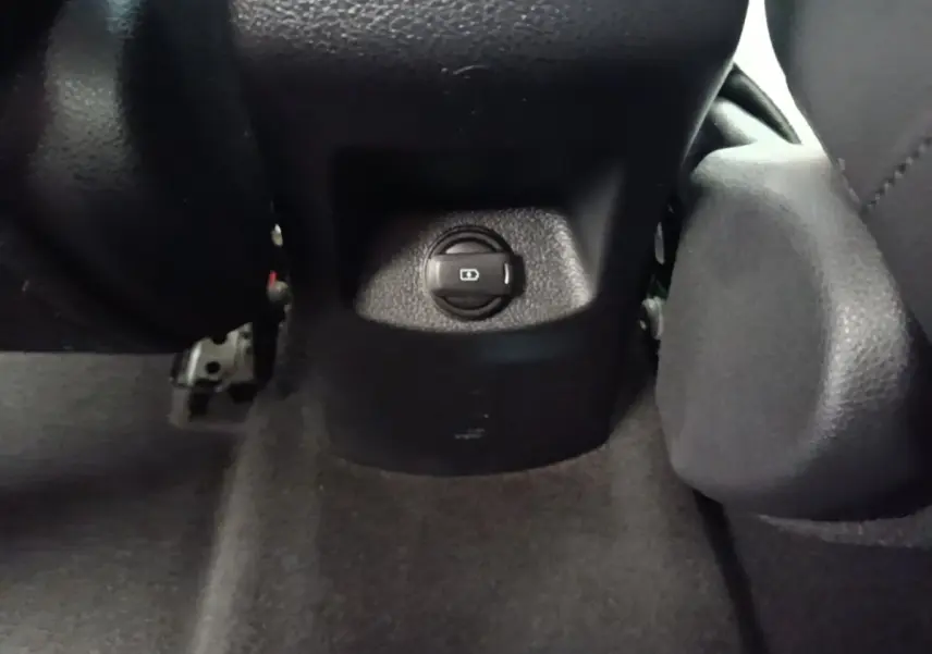Gros plan sur le bouton de réglage centralisé des rétroviseurs dans l’habitacle noir du Kia Stonic gris clair.