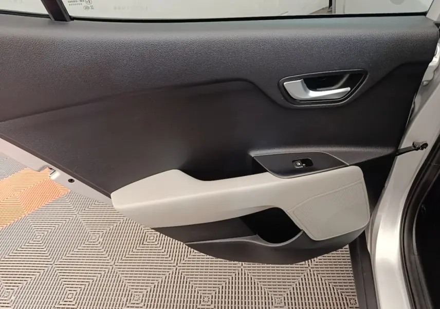 Vue intérieure côté gauche de la porte avant gris clair du KIA STONIC 2019 avec poignée argentée et accoudoir clair.