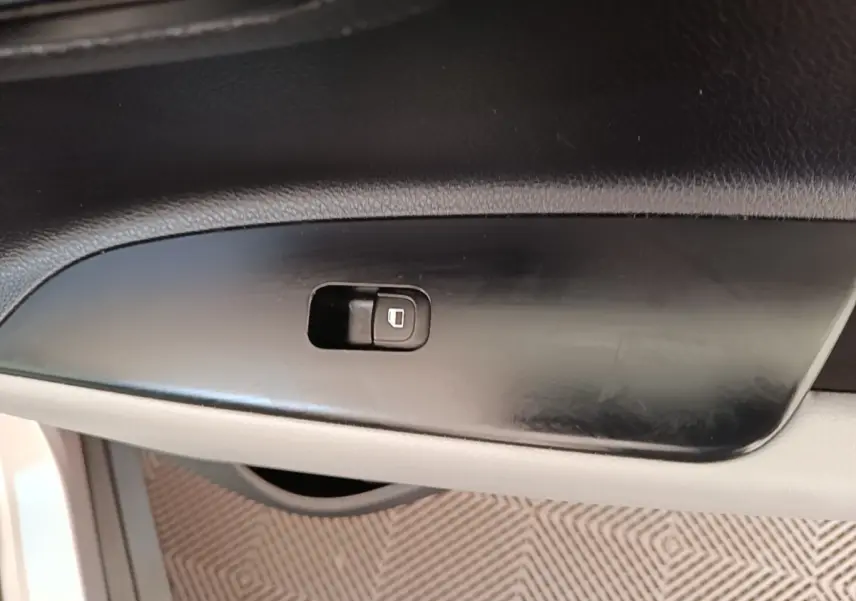 Gros plan sur le bouton de verrouillage des portes côté conducteur dans l'habitacle du KIA Stonic gris clair.
