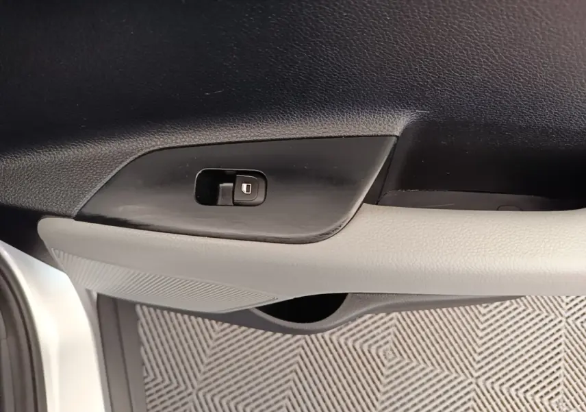 Détail de la poignée intérieure côté conducteur du KIA Stonic gris clair, avec bouton de verrouillage des portes.