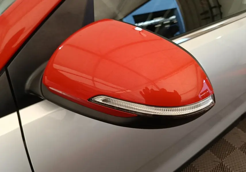 Rétroviseur droit rouge vif avec clignotant intégré sur KIA STONIC gris clair, vue rapprochée côté passager.