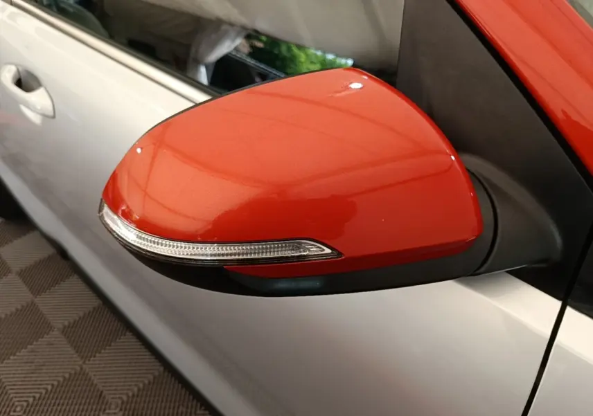 Rétroviseur droit rouge vif avec clignotant intégré sur KIA STONIC gris clair, vue rapprochée côté conducteur.
