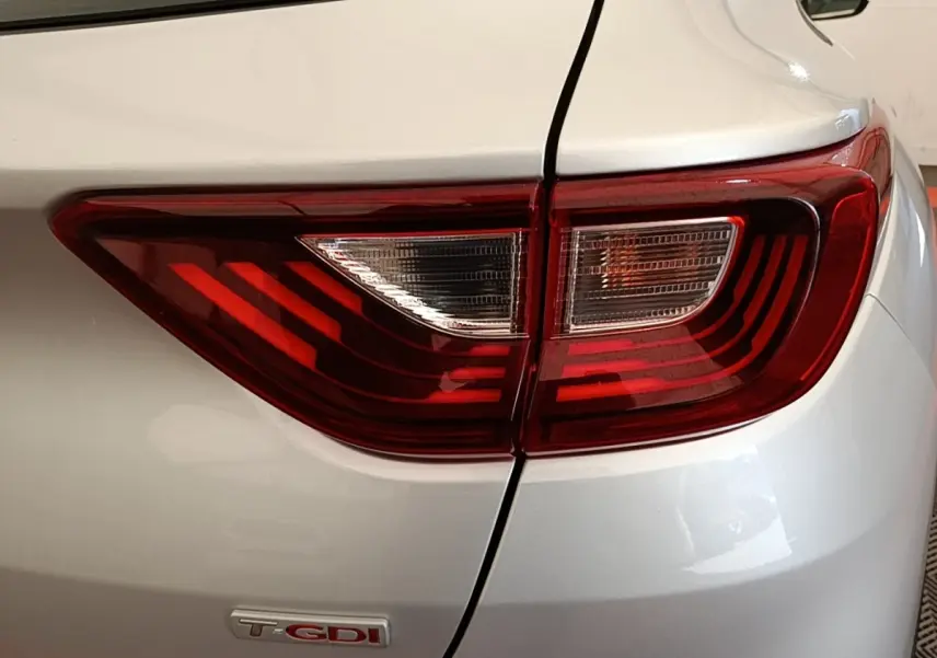 Gros plan sur le feu arrière droit rouge et blanc du KIA Stonic gris clair avec logo T-GDI visible.