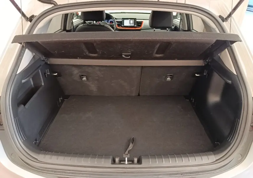 Vue arrière du coffre ouvert d'un KIA Stonic gris clair, avec intérieur noir et tablette de coffre relevée.