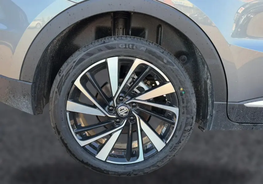 Gros plan sur la roue arrière droite gris métallisé du MG Motor ZS 1.5 hybrid 197 luxury avec jante alliage noire et argent.