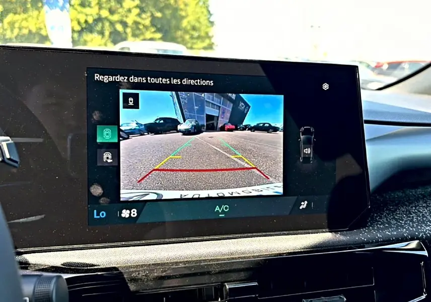 Écran tactile intérieur montrant la caméra de recul d'une Renault Clio VI noire, vue depuis le poste de conduite.