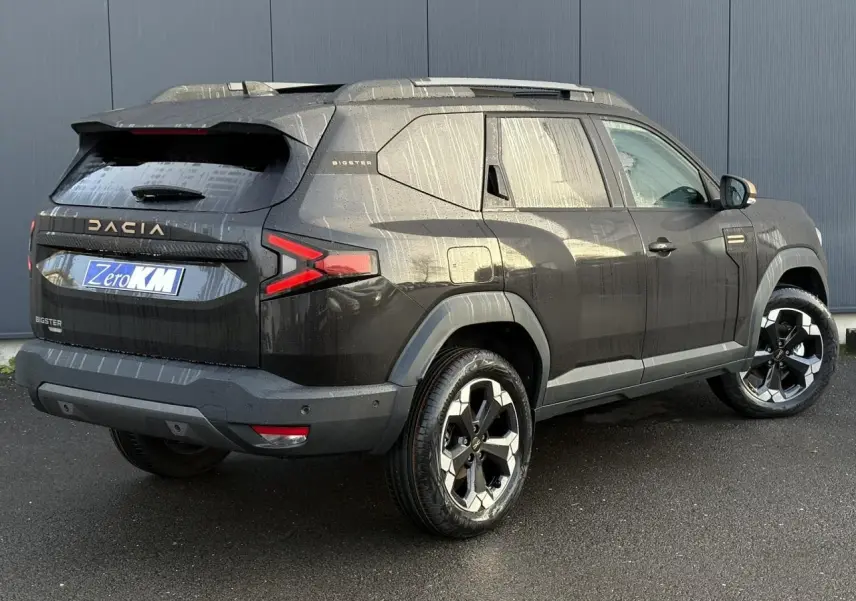 Vue 3/4 arrière droit du Dacia Bigster noir nacré avec jantes alliage 18 pouces et barres de toit modulables.