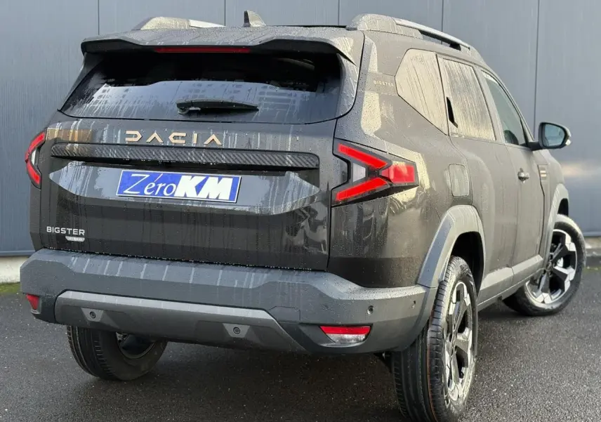Vue 3/4 arrière droite du Dacia Bigster noir nacré avec feux arrière en forme de flèche et jantes alliage noires.