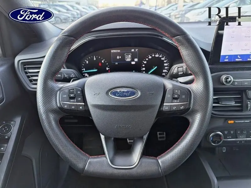 Vue rapprochée du volant cuir noir avec surpiqûres rouges de la Ford Focus 1.5 EcoBlue 2019, tableau de bord et écran tactile visibles.