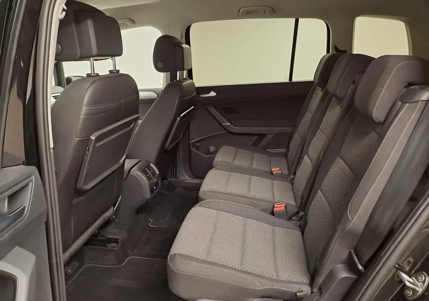 Vue intérieure côté droit sur la banquette arrière trois places du Volkswagen Touran 2025 noir intense nacré.