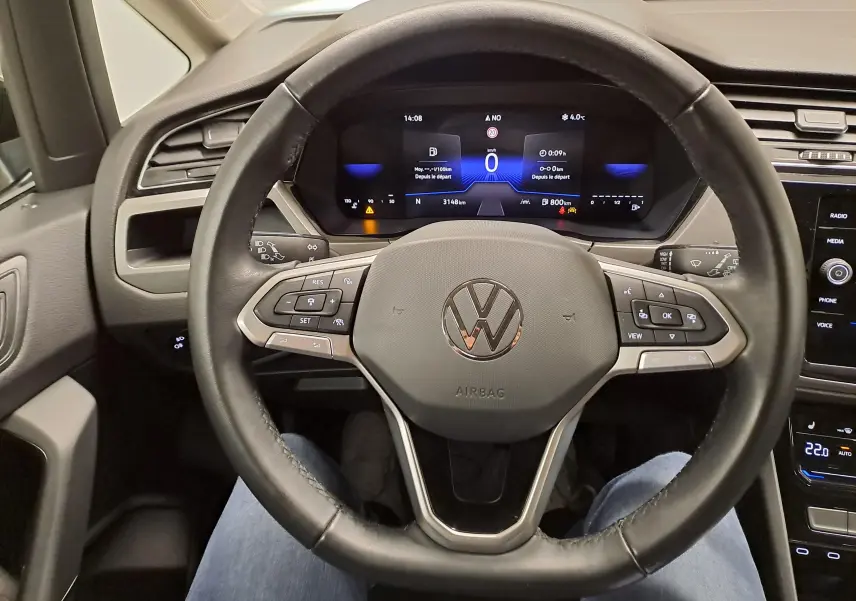 Vue intérieure centrée sur le volant multifonction noir du Volkswagen Touran 2025 avec tableau de bord numérique allumé.