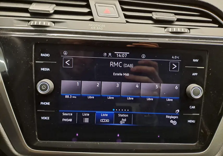 Écran tactile central du Volkswagen Touran 2025 affichant la radio DAB, avec commandes autour et finition noire brillante.