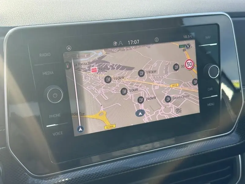 Écran tactile central du Volkswagen T-Cross 2025 affichant la navigation avec carte et points de recharge, intérieur noir.