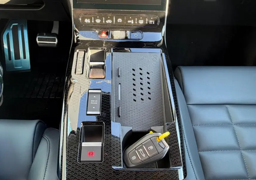 Vue rapprochée de la console centrale noire brillante du Citroën C5 Aircross avec clé et pédalier aluminium visible.