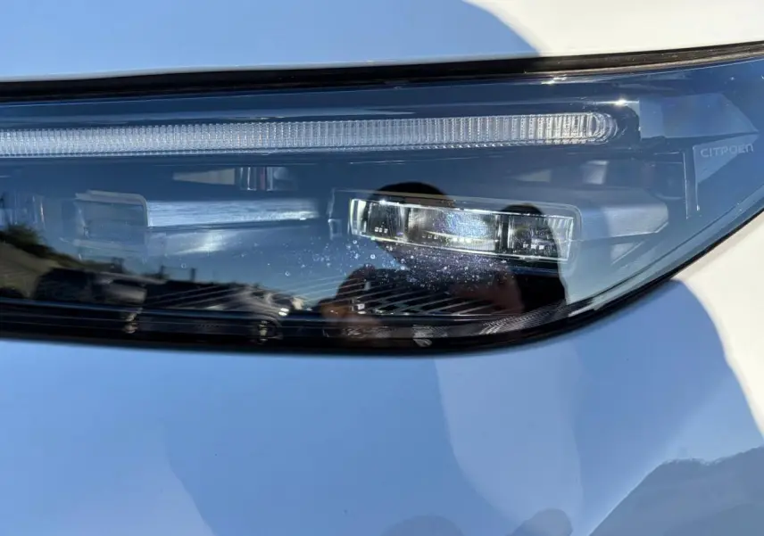 Gros plan sur le phare avant droit du Citroën C5 Aircross blanc Okenite, mettant en valeur les détails LED et la signature lumineuse.