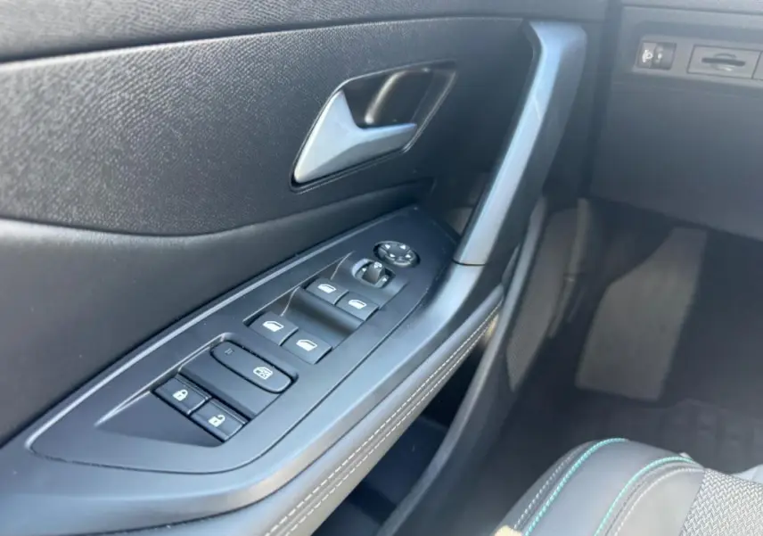 Gros plan sur la commande des vitres électriques côté conducteur de la Peugeot 308 Hybrid 136 e-DCS6 Allure noire de 2024.