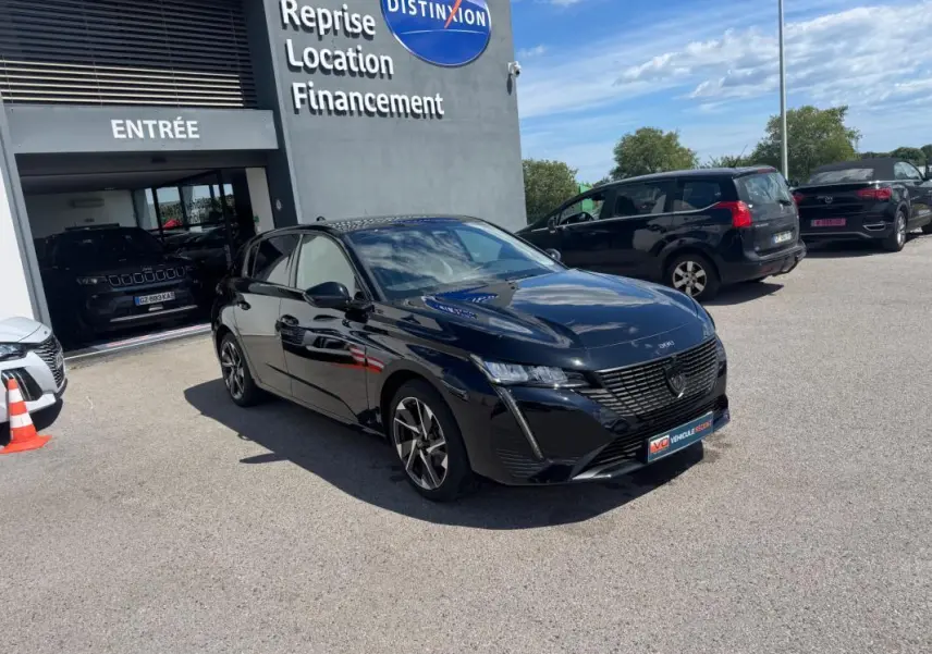 Peugeot 308 Hybrid noir vue en 3/4 avant droit, avec jantes alliage 17 pouces, stationnée devant un concessionnaire.