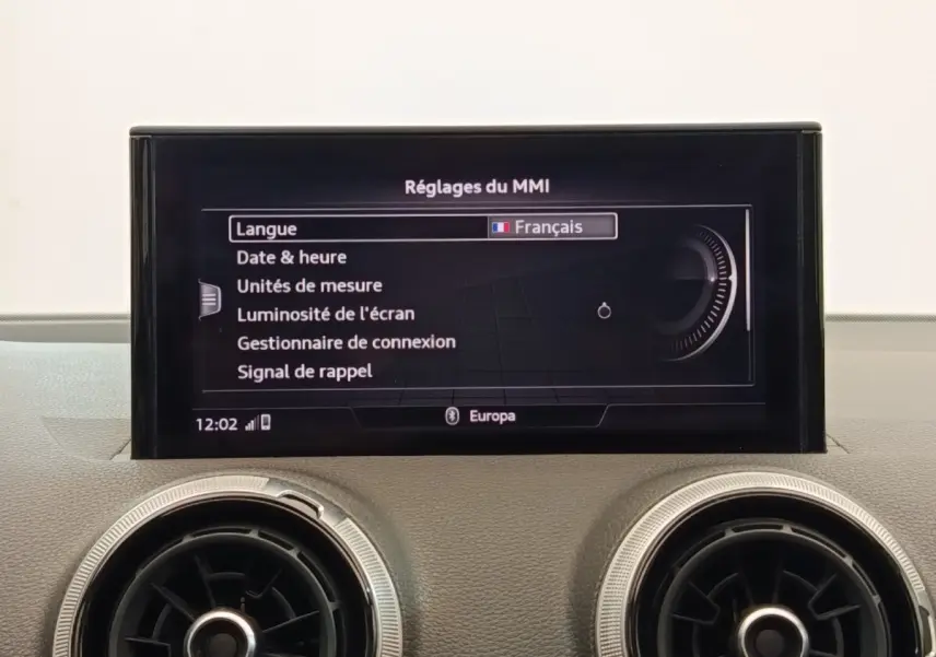 Écran central du système MMI affichant les réglages en français, avec deux aérateurs ronds en dessous, intérieur Audi Q2 2021.