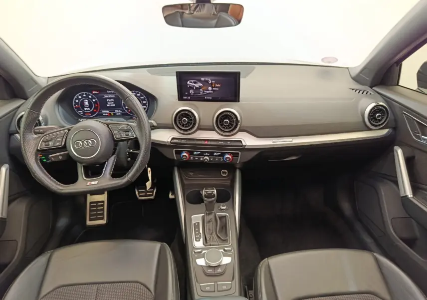 Vue intérieure avant de l'Audi Q2 noir 35 TFSI 150 S Tronic S Line, avec volant cuir multifonctions et écran central tactile.