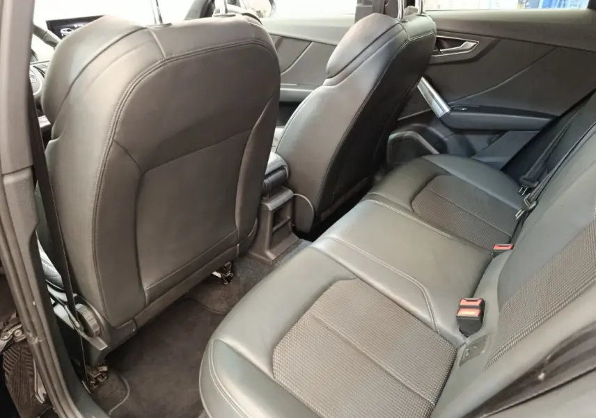 Vue intérieure arrière côté gauche de l’Audi Q2 noir, mettant en valeur la banquette 3 places en cuir et les sièges avant.