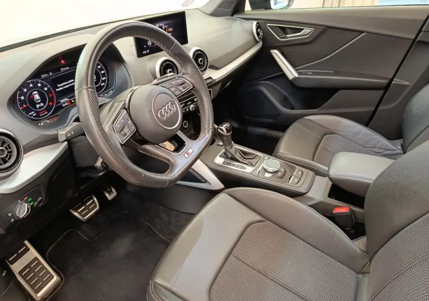 Vue intérieure côté conducteur de l'Audi Q2 35 TFSI S Line 2021, avec volant cuir et tableau de bord numérique.