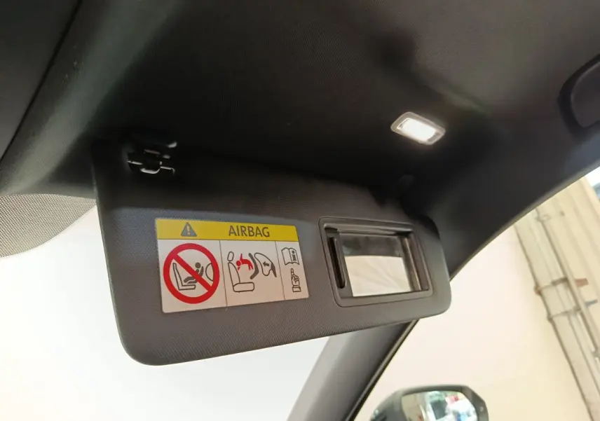 Détail du pare-soleil côté conducteur avec miroir et avertissement airbag dans l'Audi Q2 noir 2021.