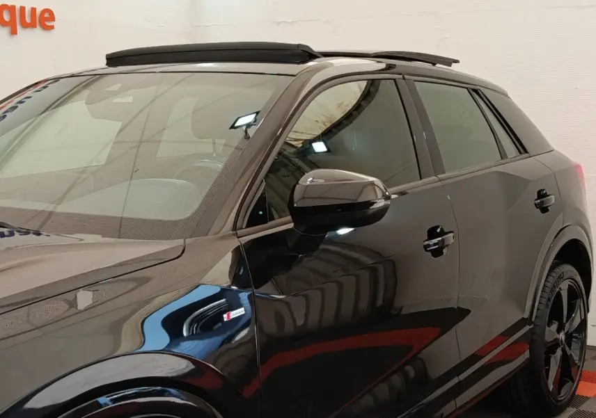 Vue de côté droit d’un Audi Q2 noir S Line 35 TFSI avec toit ouvrant et jantes noires distinctives.