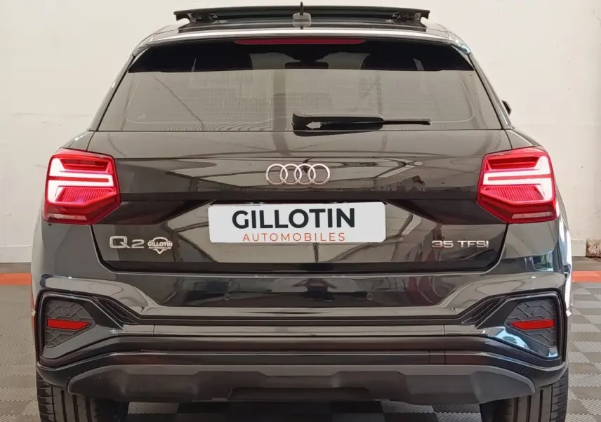 Vue arrière d’un Audi Q2 noir 35 TFSI avec feux LED et logo distinctif sur un sol à damier.