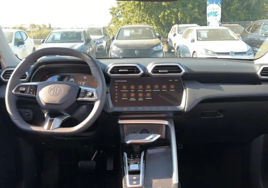 Vue intérieure frontale du tableau de bord gris du MG Motor ZS 1.5 hybrid 197 luxury avec écran tactile et volant multifonction.