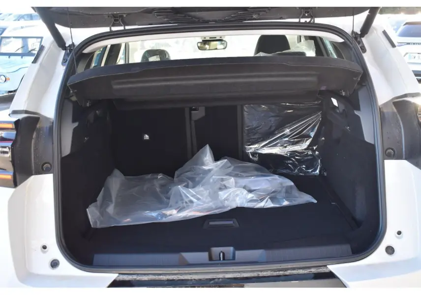 Coffre ouvert d'un Citroën C5 Aircross blanc, vue arrière, montrant l'espace de chargement avec couverture de protection noire.