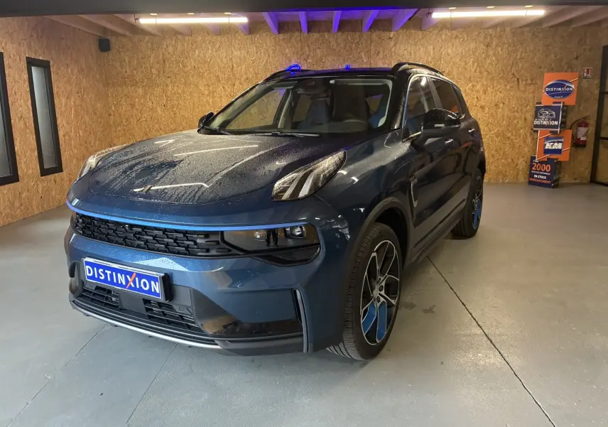LYNK & CO 01 bleu en 3/4 avant droit, SUV hybride rechargeable avec jantes bicolores et toit noir dans un garage.