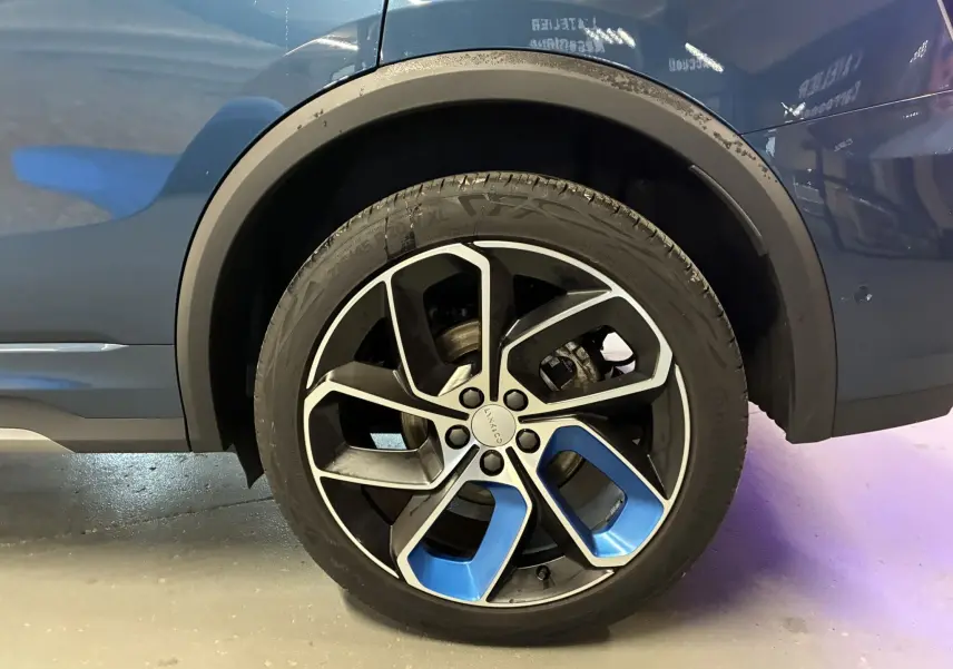 Gros plan sur la roue arrière droite bleue du LYNK & CO 01 hybride rechargeable 2023 avec jante noire et touches bleues.