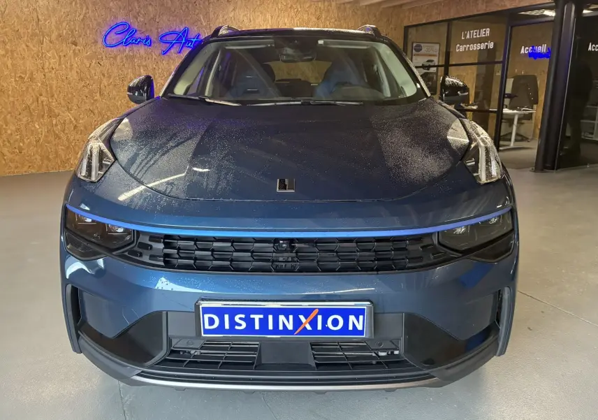 Vue frontale d'un LYNK & CO 01 bleu 2023 avec calandre noire et plaque d'immatriculation DISTINXION visible en intérieur.