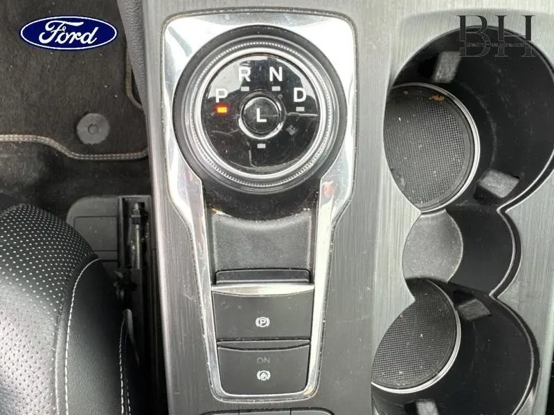 Vue rapprochée du sélecteur rotatif de boîte automatique et porte-gobelets du Ford Kuga bleu azur métallisé 2022.