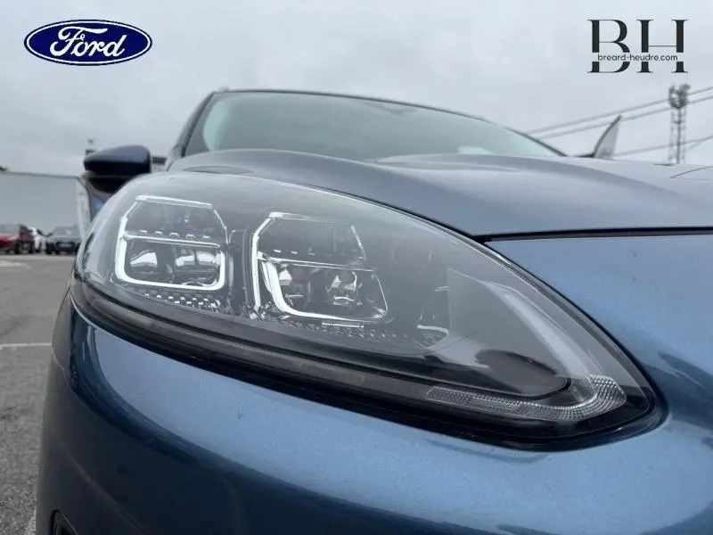 Gros plan sur le phare avant gauche du Ford Kuga bleu azur métallisé avec détails LED visibles.