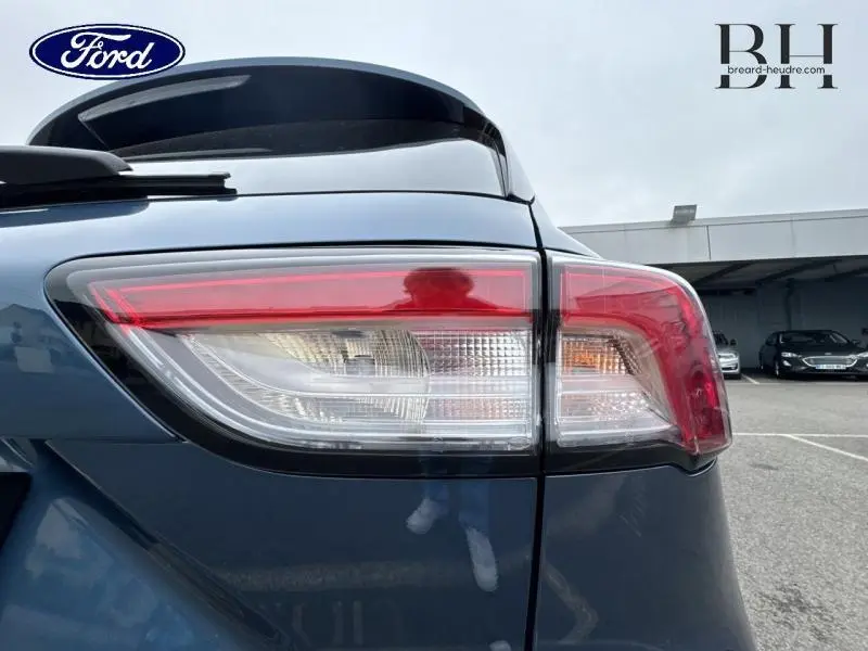 Gros plan sur le feu arrière droit du Ford Kuga 2022 bleu azur métallisé avec toit panoramique visible en arrière-plan.