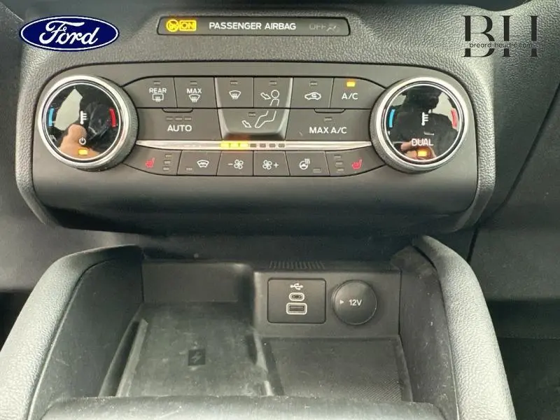 Vue rapprochée de la console centrale du Ford Kuga 2022, montrant les commandes de climatisation et prises USB et 12V.