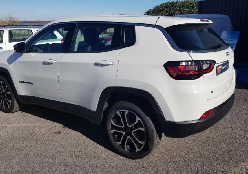Vue 3/4 arrière droite d’un Jeep Compass blanc 2024 avec jantes alliage 18 pouces et vitres teintées.