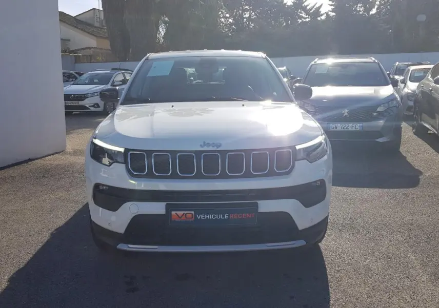 Vue avant d'un Jeep Compass blanc 2024 avec calandre distinctive et phares LED allumés en extérieur.