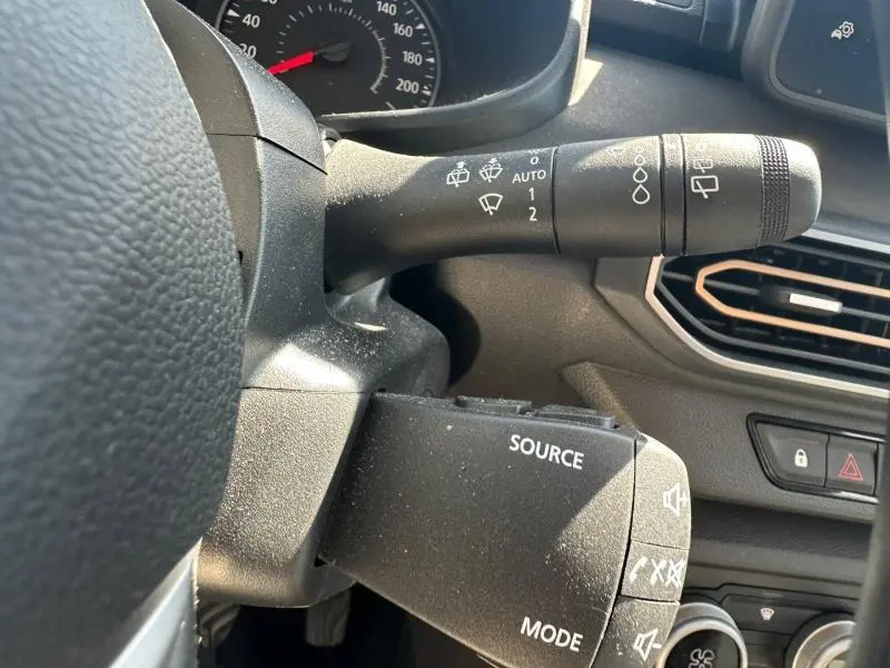 Gros plan sur la commande d’essuie-glace et les boutons audio au volant dans l’habitacle d’une Dacia Sandero 2025.