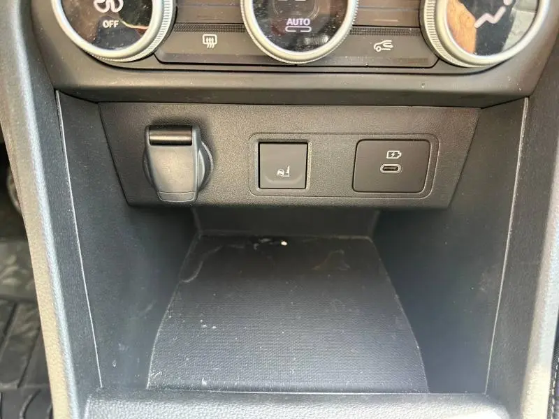 Vue rapprochée de la console centrale noire de la Dacia Sandero 2025 avec prises USB et bouton de frein à main électrique.