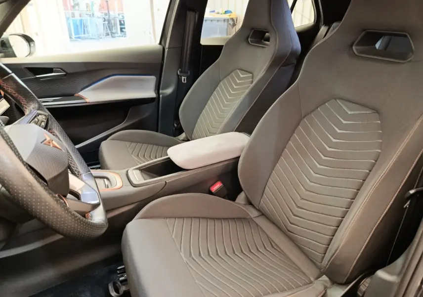 Vue intérieure côté conducteur du CUPRA Born 230ch gris foncé, avec sièges sport et volant cuir multifonctions.
