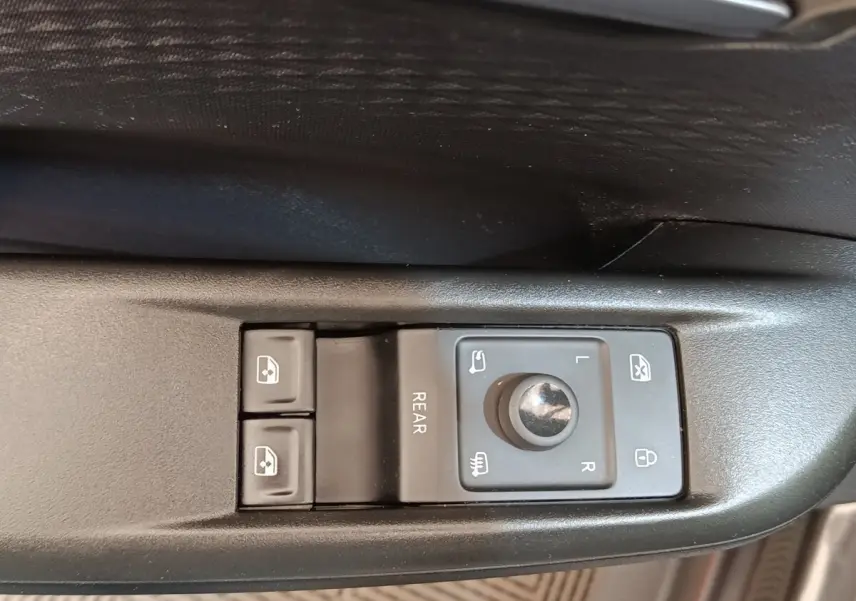 Gros plan sur les commandes de réglage des rétroviseurs et des vitres côté conducteur d'une CUPRA BORN gris foncé.