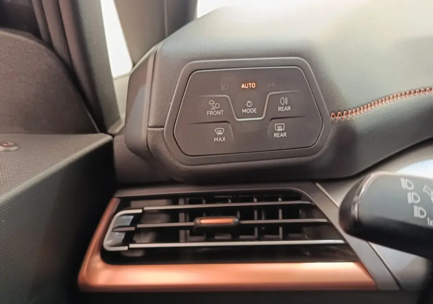 Détail du tableau de bord côté gauche avec commandes d’éclairage et grille d’aération cuivrée dans une CUPRA Born gris foncé.