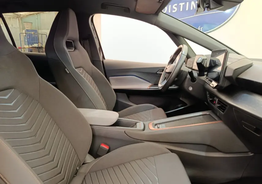 Vue intérieure côté droit de la CUPRA Born 230ch gris foncé, avec sièges sport et écran tactile central vertical.